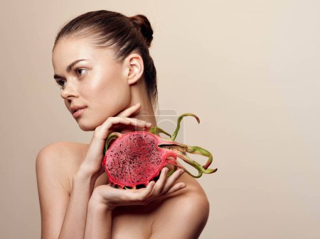 Photo for Young woman holding exotic dragon fruit on beige background in a beautiful and vibrant composition - Royalty Free Image