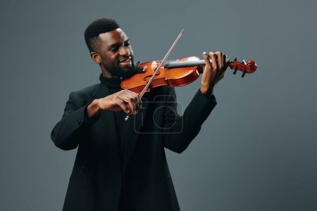 Músico afroamericano tocando el violín en una actuación cautivadora sobre un fondo gris