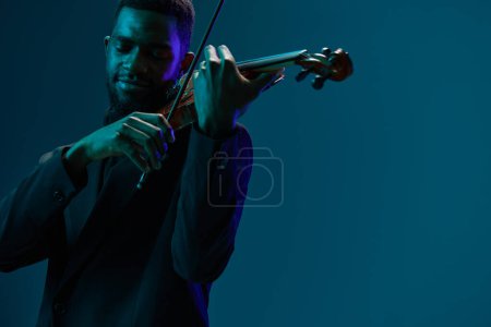 Photo for Elegant musician in formal attire playing the violin with passion on a vibrant blue background - Royalty Free Image