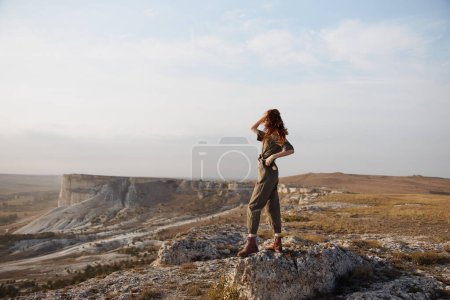Mujer de pie con orgullo en la roca en el paisaje del desierto con las manos en las caderas, aventura de viaje y el concepto de exploración