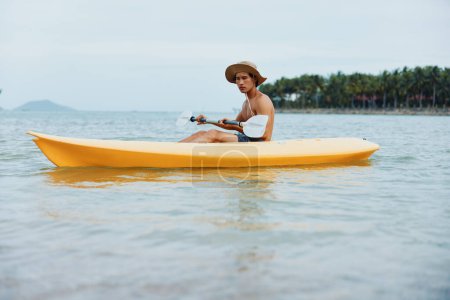 Téléchargez les photos : Heureux asiatique homme appréciant kayak aventure sur tropical plage - en image libre de droit