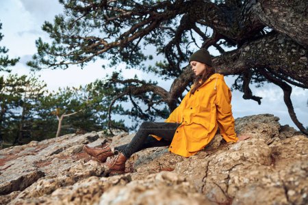 A peaceful moment in nature woman in a vibrant yellow raincoat enjoys a relaxing break by the tree