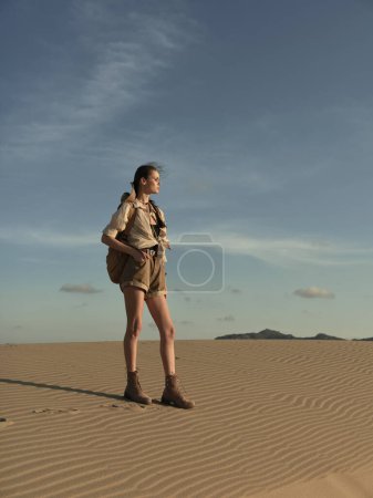 Einsame Frau steht in der weiten Wüstenlandschaft und blickt in den unbekannten Horizont