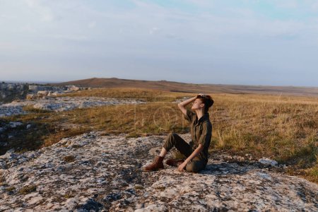 Photo for Solitude a person enjoying tranquility on top of a rock in the middle of a grassy field - Royalty Free Image