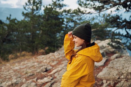 A woman in a bright yellow raincoat admiring the stunning mountain landscape during a travel adventure