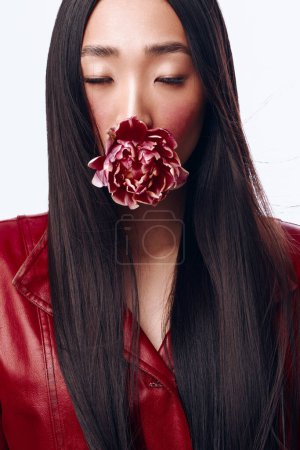 Mujer misteriosa con el pelo negro cubriéndose la boca con un delicado retrato de flores