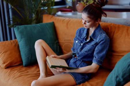 Woman leisurely reading book on vibrant orange couch in cozy home environment with natural lighting