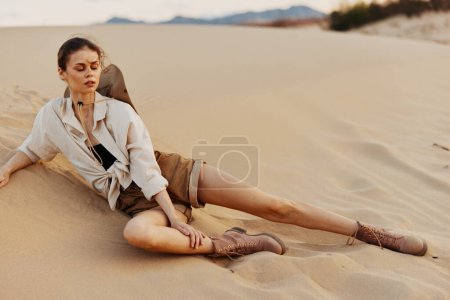 Woman enjoying the view from a sand dune in white shirt and brown boots