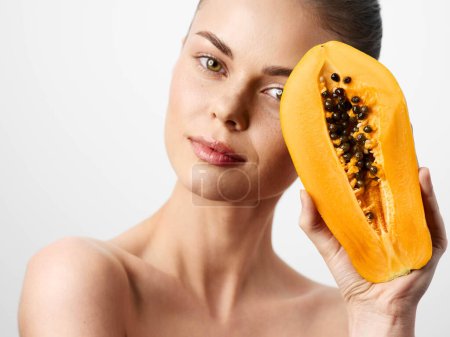 Belle jeune femme avec masque facial aux fruits de papaye isolé sur fond blanc, concept de soins et de beauté