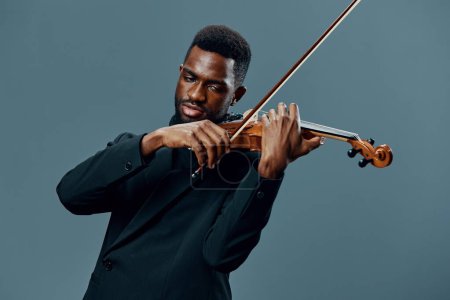 Elegant African American Violinist in Black Suit Performing on Gray Background in Classic Music Concert Theme