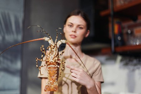 Woman Holding Lobster in Hand Standing in Front of Kitchen Counter, Food Preparation Concept