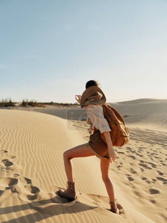 Desierto aventura Mujer con mochila deambulando por las dunas de arena en un día soleado en un paisaje pintoresco