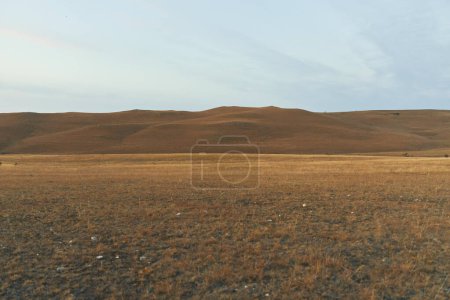 Trostlose Wüstenlandschaft mit grasbewachsener Ebene und Hügeln im Hintergrund, Naturreise-Abenteuerkonzept