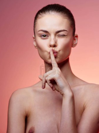 Heitere und sinnliche junge Frau macht eine ruhige Geste mit Zeigefinger auf den Lippen