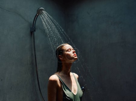 Woman enjoying a soothing shower as water cascades down her body from the faucet, creating a serene and relaxing moment.