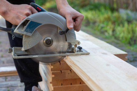 Photo for A carpenter cuts wooden floorboards with a circular saw - Royalty Free Image
