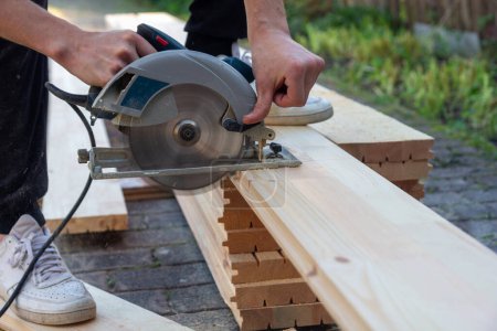 Photo for A carpenter cuts wooden floorboards with a circular saw - Royalty Free Image