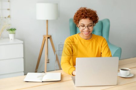 African american girl using laptop at home office looking at screen typing chatting reading writing email. Young woman having virtual meeting online chat video call conference. Work learning from home Poster 643044346