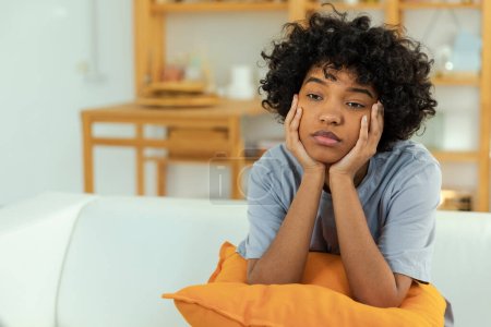 Foto de African american sad thoughtful girl at home. Young african woman feels depressed offended lonely upset suffers from abuse harassment heartbreak. Grieving violence victim has psychological problem - Imagen libre de derechos