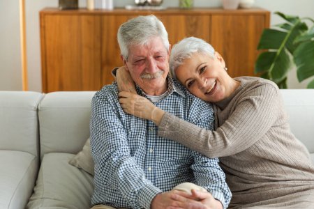 Photo for Senior adult mature couple hugging at home. Mid age old husband and wife embracing with tenderness love enjoying sweet bonding wellbeing. Grandmother grandfather together. Family moment love and care - Royalty Free Image