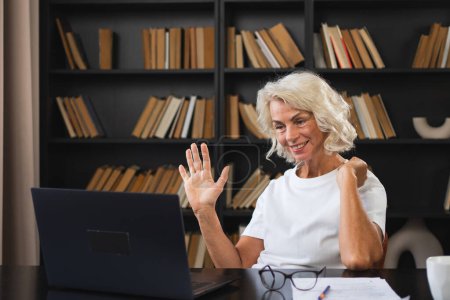 Video call. Happy middle aged senior woman sit with laptop talk on video call. Mature old senior lady having fun talking speaking online. Older generation modern tech usage Virtual meeting online chat