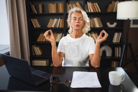 Yoga méditation pleine conscience Aucun stress garder calme. Femme d'âge moyen pratiquant le yoga au bureau. Femme prenant une pause du travail méditant relaxant. Femme mûre faisant pratique respiratoire yoga en ligne au travail