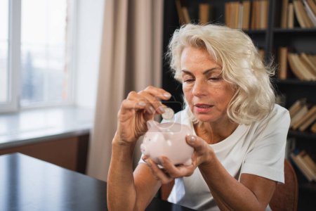 Saving money investment for future. Senior adult mature woman putting money coin in piggy bank. Old grandmother counting saving money planning retirement budget. Investment banking concept