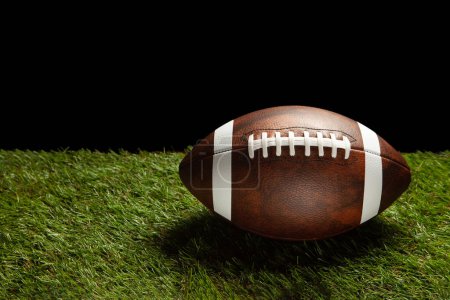 Foto de American football ball on green grass field background with space for text. - Imagen libre de derechos