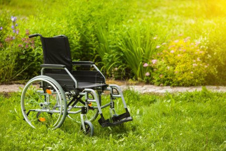 Photo for Empty wheelchair in the garden or in the park. Wheelchair in the grass in the garden. - Royalty Free Image