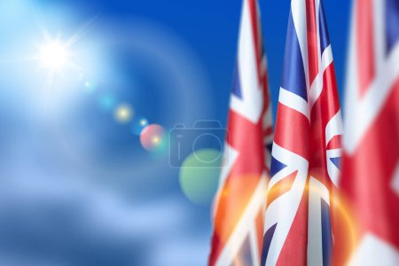 Téléchargez les photos : National flags of United Kingdom on a flagpole on blue sky background. Lowered UK flags. Background with place for your text. - en image libre de droit