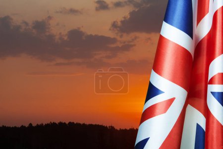 Téléchargez les photos : Drapeaux nationaux du Royaume-Uni sur un mât de drapeau sur fond de ciel couchant. Baisse des drapeaux britanniques. Contexte avec place pour votre texte. - en image libre de droit