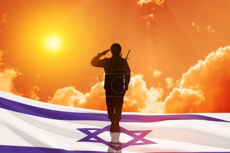 Foto de Silueta de soldado saludando contra el amanecer en el desierto y la bandera de Israel. Concepto - Fuerzas Armadas de Israel. - Imagen libre de derechos