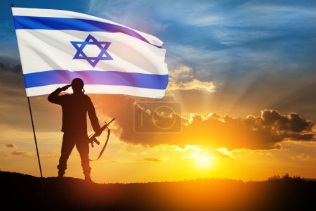 Photo for Silhouette of soldier saluting with Israel flag against the sunrise in the desert. Concept - armed forces of Israel. - Royalty Free Image
