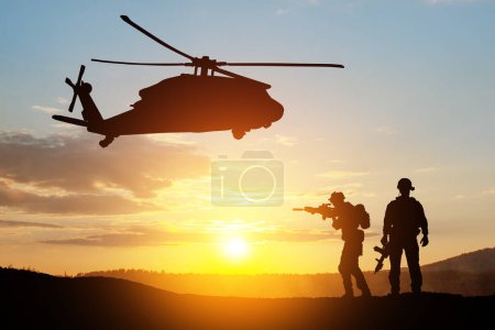 Foto de Siluetas de helicóptero y soldados en el fondo de la puesta del sol. Tarjeta de felicitación para el Día de los Veteranos, Día de los Caídos, Día de la Fuerza Aérea. Celebración USA. - Imagen libre de derechos