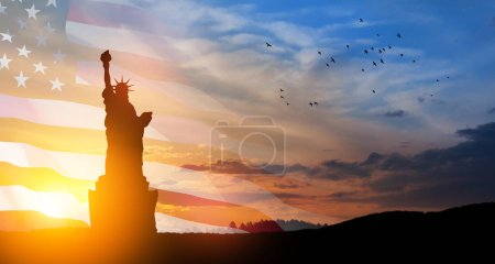 Foto per Statue of Liberty with a large american flag and sunset sky with flying birds on background. Greeting card for Independence Day. USA celebration. - Immagine Royalty Free