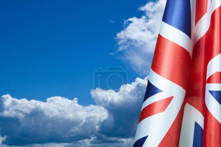 Téléchargez les photos : National flags of United Kingdom on a flagpole on blue sky background. Lowered UK flags. Background with place for your text. - en image libre de droit
