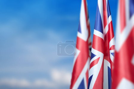 Téléchargez les photos : Drapeaux nationaux du Royaume-Uni sur un mât de drapeau sur fond bleu ciel. Baisse des drapeaux britanniques. Contexte avec place pour votre texte. - en image libre de droit