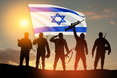 Silhouetten von Soldaten mit israelischer Flagge gegen den Sonnenaufgang in der Wüste. Konzept - Streitkräfte Israels.