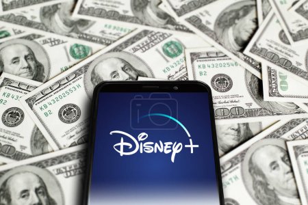 Téléchargez les photos : Logo Disney Plus sur l'écran du smartphone sur fond de dollars. Dinsey plus est un service de streaming vidéo sur demande par abonnement américain. Moscou, Russie - 1 novembre 2022. - en image libre de droit