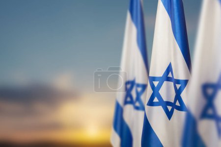 Israël drapeaux avec une étoile de David sur fond de ciel nuageux sur le coucher du soleil. Concept patriotique sur Israël avec des symboles nationaux de l'État. Bannière avec place pour le texte.