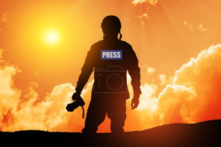 Foto de Photojournalist silhouette documenting war or conflict. Photojournalist at sunset. War, army, technology and journalist work concept. - Imagen libre de derechos