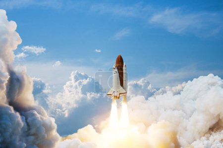 Téléchargez les photos : Spaceship lift off. Space shuttle with smoke and blast takes off into space on a background of blue sky. Successful start of a space mission. Elements of this image furnished by NASA. - en image libre de droit