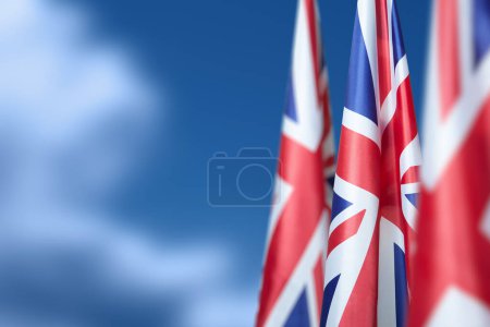 Téléchargez les photos : Drapeaux nationaux du Royaume-Uni sur un mât de drapeau sur fond bleu ciel. Baisse des drapeaux britanniques. Contexte avec place pour votre texte. - en image libre de droit