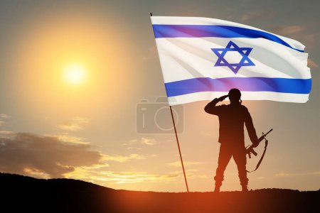 Silueta de soldado saludando con bandera de Israel contra el amanecer en el desierto. Concepto - Fuerzas Armadas de Israel.