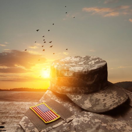 USA military uniform with insignias on old wooden table on sunset sky background with flying birds. Memorial Day or Veterans day concept.