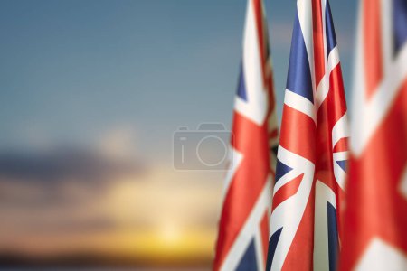 Téléchargez les photos : Drapeaux nationaux du Royaume-Uni sur un mât de drapeau sur fond de ciel couchant. Baisse des drapeaux britanniques. Contexte avec place pour votre texte. - en image libre de droit