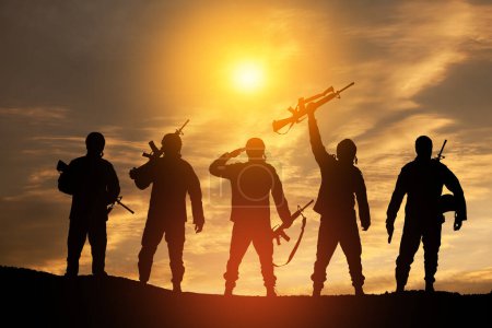 Téléchargez les photos : Silhouettes of soldiers standing against the backdrop of a sunset. Greeting card for Veterans Day, Memorial Day, Independence Day. USA celebration. Concept - patriotism, protection, remember honor. - en image libre de droit
