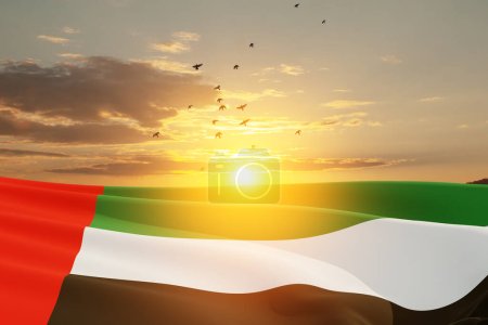 Flag of United Arab Emirates on background of sunset sky with flying birds. UAE celebration. National day, Flag day, Commemoration day, Martyrs day.