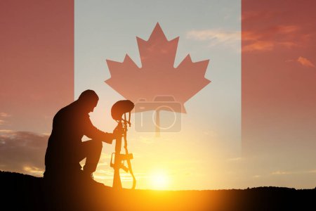 Silueta de soldado arrodillado con la cabeza inclinada sobre un fondo de atardecer o amanecer y bandera de Canadá. Tarjeta de felicitación para el Día de la Amapola, Día del Recuerdo. Celebración en Canadá. Concepto - patriotismo, honor.