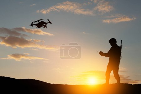 Foto de Silhouettes of soldiers are using drone and laptop computer for scouting during military operation against the backdrop of a sunset. Greeting card for Veterans Day, Memorial Day, Independence Day. - Imagen libre de derechos